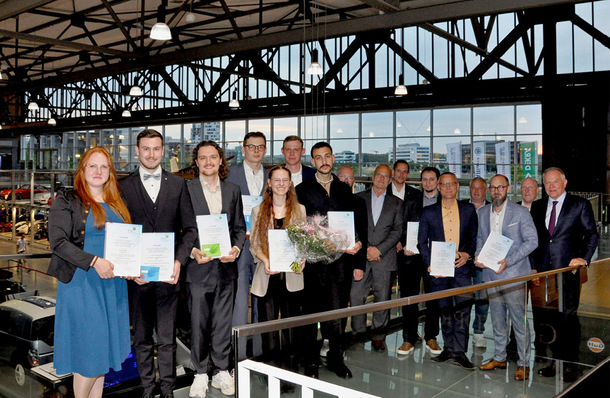 Gerne! Hier ist der optimierte, themen- und zielgruppenrelevante Alt-Text: Alt-Text: „Mehrere junge SHK-Absolventinnen und Absolventen stehen in Berufskleidung mit Urkunden und Blumen in der Hand bei einer Abschlussfeier in einem modernen Gebäude.“ Begründung: Der Text benennt konkret die Situation (Abschlussfeier im SHK-Handwerk), die Zielgruppe (junge Fachkräfte), relevante Details (Berufskleidung, Urkunden) sowie den Kontext (modernes Gebäude). So erhalten auch Menschen mit Seheinschränkung einen aussagekräftigen Eindruck vom Bildinhalt. - © Bild: ja / BTGA e.V.