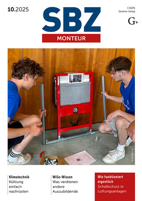 Zwei Personen montieren mit Werkzeugen einen roten Metallrahmen vor einer Holzwand.